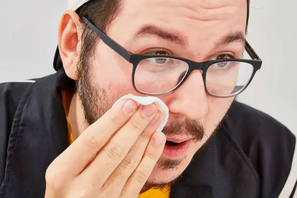 Person wiping face with a cotton round of micellar water