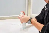 Person dispensing Mustela Baby Cleansing Water onto cotton round