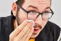 Person wiping face with a cotton round of micellar water