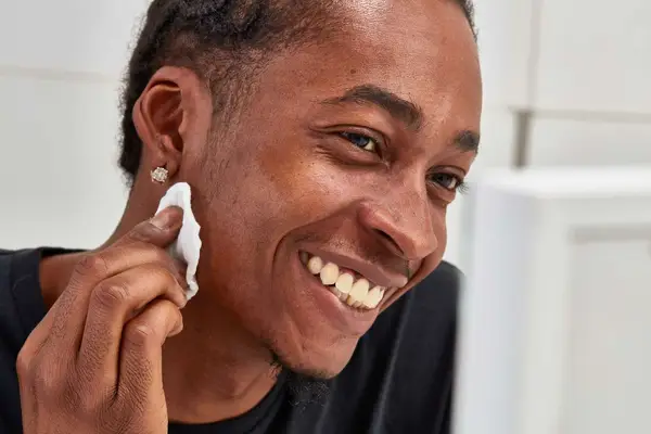 Person applying Simple Kind to Skin Micellar Cleansing Water to their face