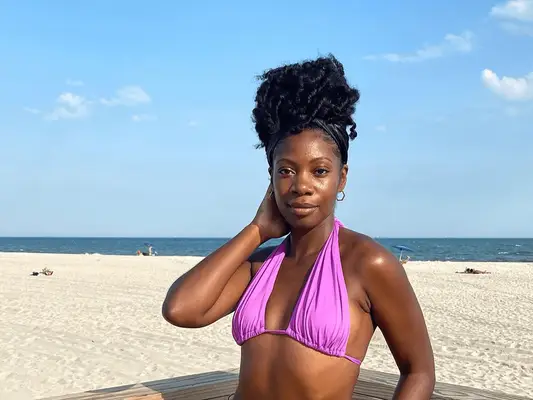 woman standing on beach in purple bathing suit