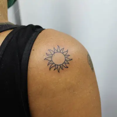Small circular sun outline shoulder tattoo