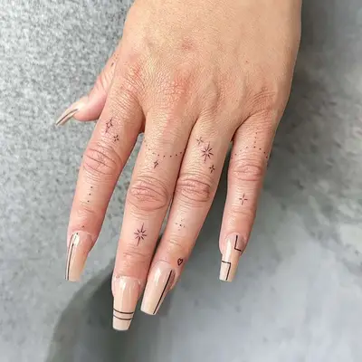 A hand with several small star and dot hand tattoos