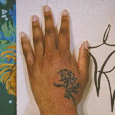Close up of a flower tattoo on a hand, the hand against a way