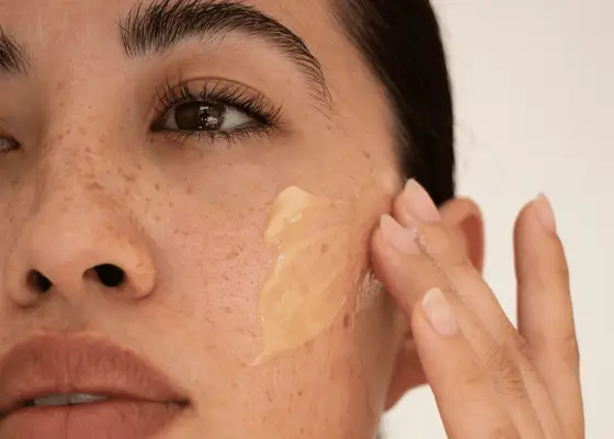 Woman with freckles swiping a cleansing balm on her cheek