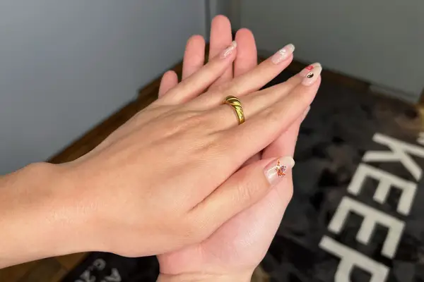 A pair of hands with painted nails and a gold ring