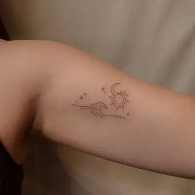 image of black ink fine line tattoo on arm of waves, sun, moon, stars