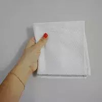 Hand holding a folded Coyuchi Mediterranean Organic Washcloth against white background