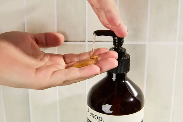 Person dispenses Aesop Geranium Leaf Body Cleanser into their hand