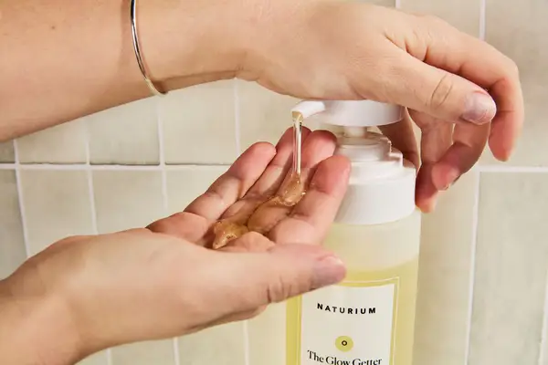 Person dispenses Naturium The Glow Getter Multi-Oil Hydrating Body Wash into their hand