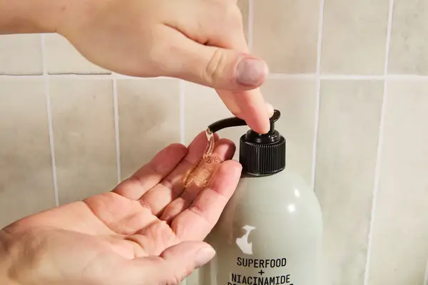 Person dispenses Youth To The People Superfood + Niacinamide Body Cleanser into their hand