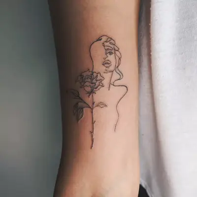 A close up of a portrait tattoo of a woman paired with a rose.