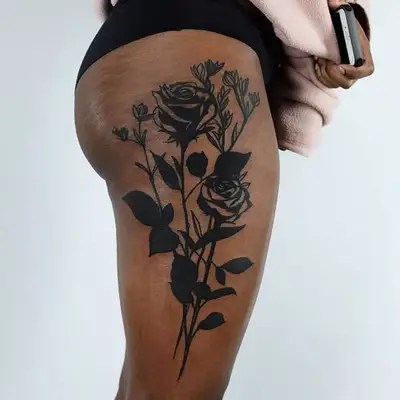 A close up of a rose stem thigh tattoo.