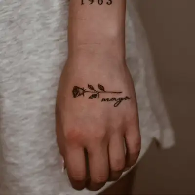 Close up of a hand with a black line rose stem tattoo.