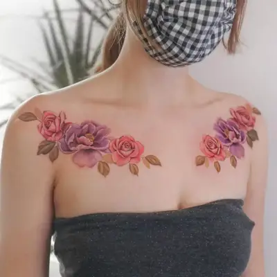 Close up of a modle with pink and purple rose and flower collarbone tattoos.