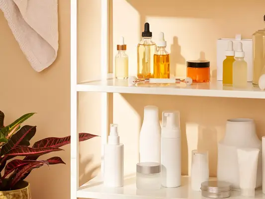 Skincare products in clear and white bottles on bathroom shelving unit