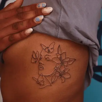 custom tattoo of face outline with butterflies and flowers