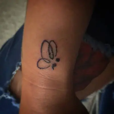 Wrist with butterfly semicolon tattoo