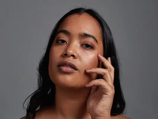 Woman with clear skin touches her face