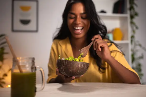 woman with dark hair enjoying salad and green juice