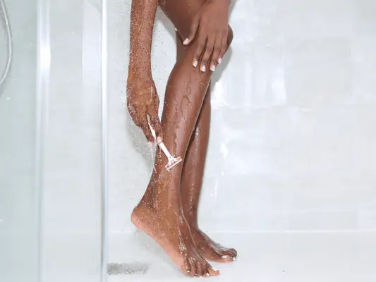 woman shaving legs in the shower