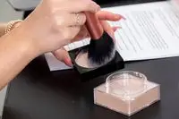 woman applying Maybelline Fit Me Loose Finishing Powder to brush