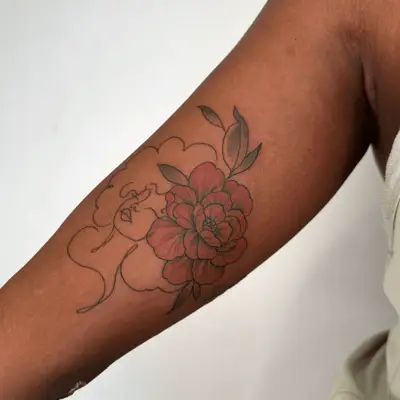 Female silhouette with flower in hair arm tattoo