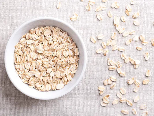 A bowl of oats with some sprinkled on the side, too. 