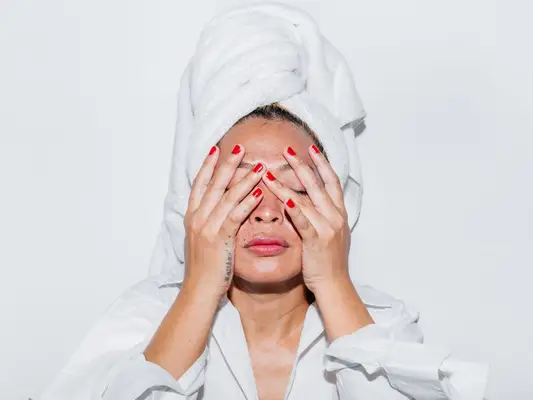 Person with a towel on their head touching their face