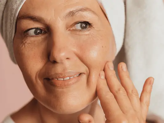 woman touching clear skin against pink background