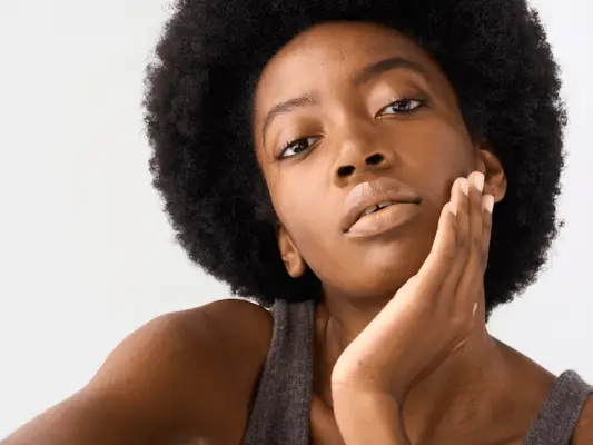 Close up of a woman with clear skin and her hand on her face