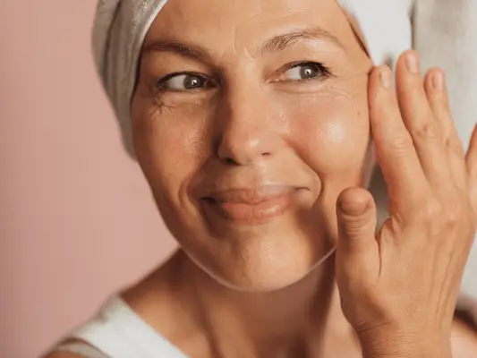 Close up of a woman smiling, displaying under eye wrinkles.