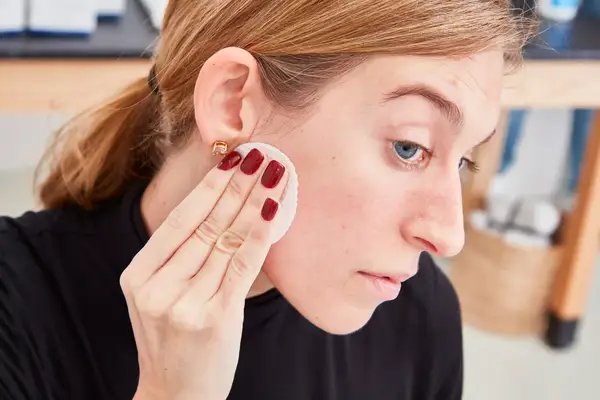 Person rubbing their face with a cotton pad 