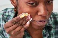 Person rubbing their cheek with a cotton round