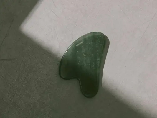 green gua sha stone on gray background