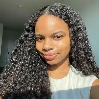 MYM Beauty editor Olivia Hancock with glowing skin and natural defined curls in sunlight