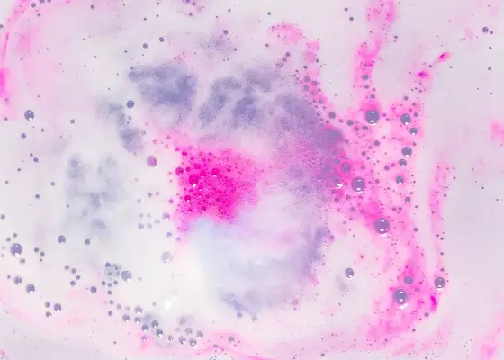 close up of pink bath bomb fizzing in tub water