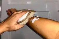 A person uses the Almooni Natural Loofah Exfoliating Body Scrubber on their arm