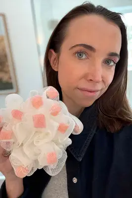 A person holds up the ecoTools Lathering EcoPouf Bath Sponge