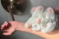 A person scrubs their arm with the ecoTools Lathering EcoPouf Bath Sponge