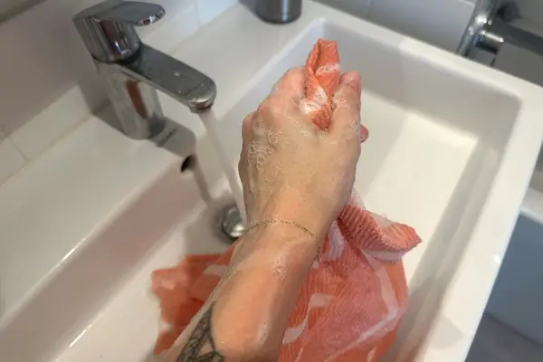 A person lathers the Hanni Shower Scarf with soap
