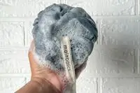 A person lathers soap into the MainBasics Main Basics Bath Shower Loofah
