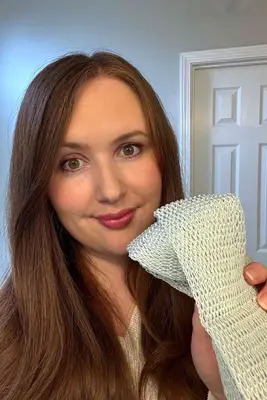 A person holds up the LuvScrub Mesh Body Exfoliator