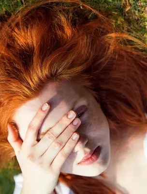 Red-headed woman with hand on face
