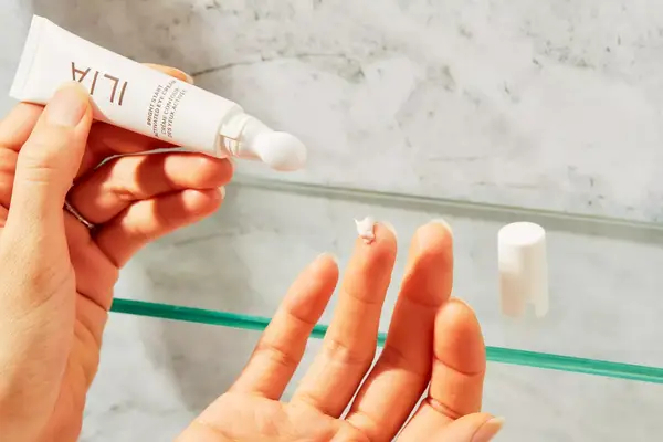 Person applying ILIA Bright Start Retinol Alternative Brightening Eye Cream to finger