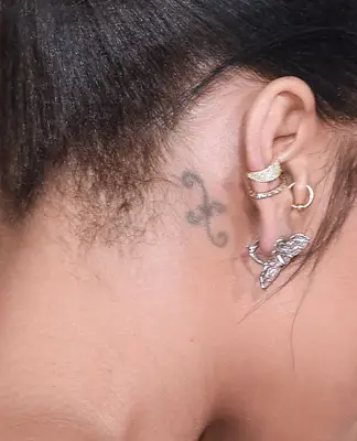 Rihanna with scroll-like behind the ear tattoo