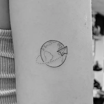 Arm tattoo with paper airplane circling globe