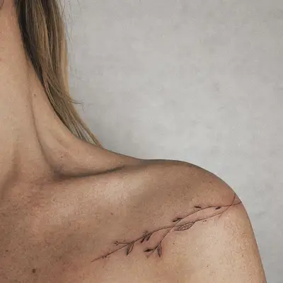 Shoulder tattoo with delicate leafy branch