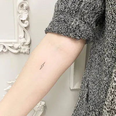 Thin lightning bolt tattoo on forearm