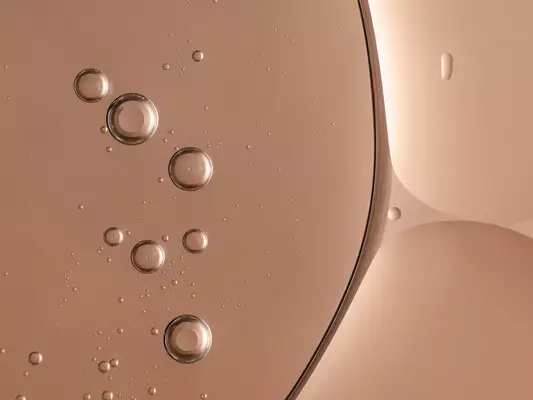 a skincare serum backlit with pink tone. bubbles and round shapes and highlights in the texture